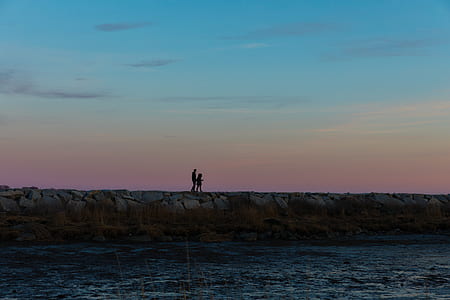 silhouette of two persons standing on cliff thumbnail