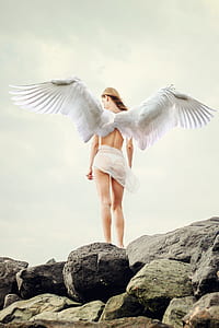 angel standing on rock under cloudy sky thumbnail
