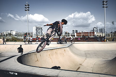 man riding BMX bike under white clouds thumbnail