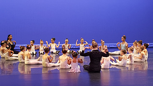 children and two women wearing ballet costumes sitting on floor thumbnail