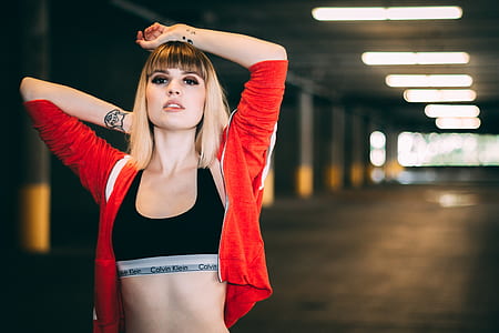 smiling woman in black Calvin Klein sports bra and red jacket thumbnail