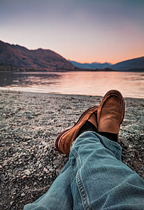 person sitting on sand beside lake thumbnail