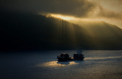 boat on body of water near silhouette of mountains during daytime thumbnail