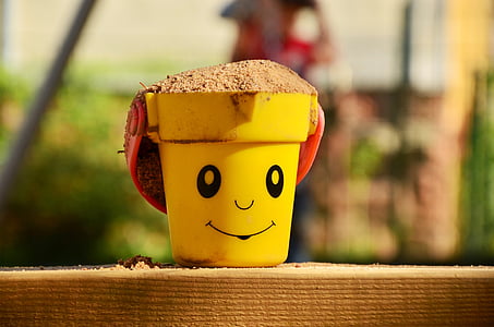shallow focus photography of yellow bucket filled with brown sand thumbnail