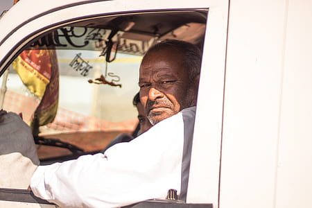 man in white long-sleeved top sitting inside vehicle during daytime thumbnail