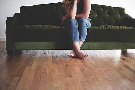 woman in blue jeans seating on green couch thumbnail