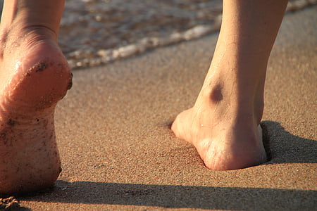 shallow focus photography person's foot standing on beach sand during daytime thumbnail