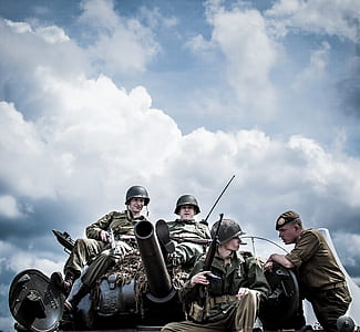 four men sitting on tank under cloudy sky thumbnail