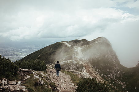 person walking on brown mountain under blue and white sky thumbnail
