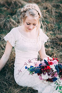 woman holding flower bouquet sitting on grass thumbnail
