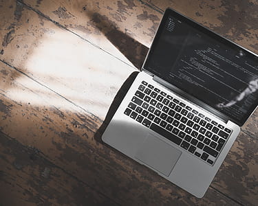 MacBook Pro open on brown wooden surface thumbnail
