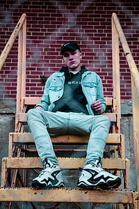 man wearing blue denim stonewashed zip-up western jacket sitting on yellow metal stairs thumbnail