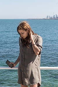 woman holding smartphone while leaning on white boat handrail thumbnail