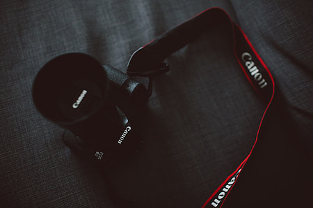 black Canon DSLR camera on gray textile thumbnail