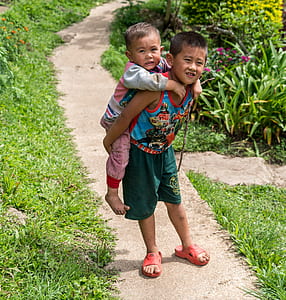 boy carrying child on pathway thumbnail
