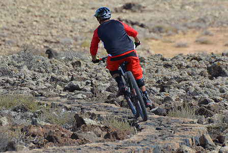 man riding a bicycle on rock field thumbnail