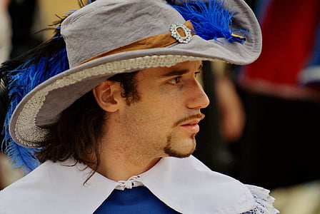 man wearing gray and blue feather hat thumbnail