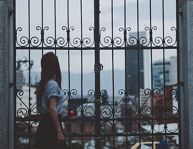woman standing against brown metal gate thumbnail