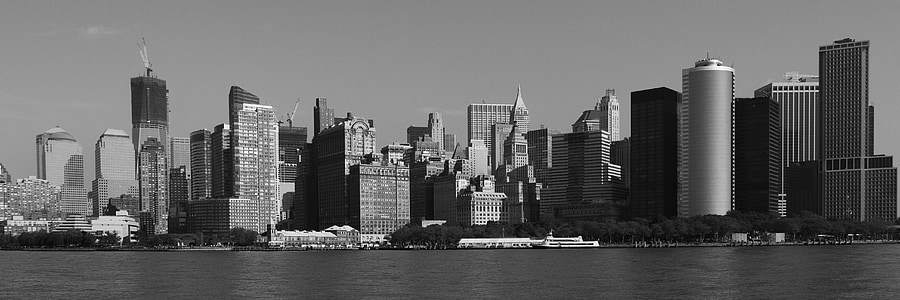 grayscale photo of cityscape by water thumbnail