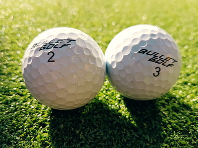 two white-and-black Bullet Golf 3 and 2 balls on green grass thumbnail