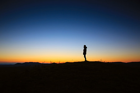 silhouette photography of man standing on peak thumbnail
