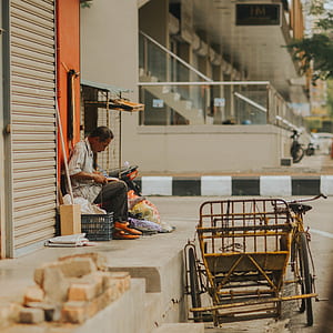 man sitting beside building thumbnail