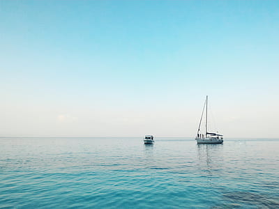 two boats on body of water under white clouds and blue sky thumbnail