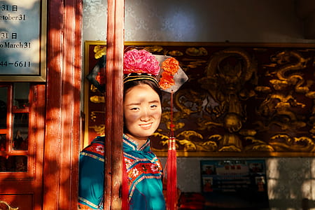 smiling woman with red floral head dress standing near wall art thumbnail