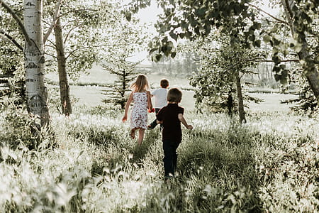 three children running on grass field at daytime thumbnail