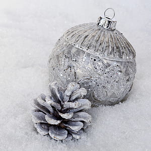 silver glitter bauble and white painted pine cone on fur textile thumbnail