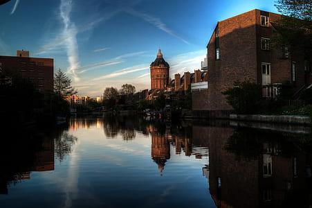 gray concrete buildings near river with reflection during daytime thumbnail
