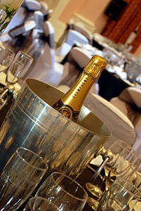 selective focus photography of wine bottle in round gray metal bucket surrounded by clear wine glasses on top of table inside room thumbnail