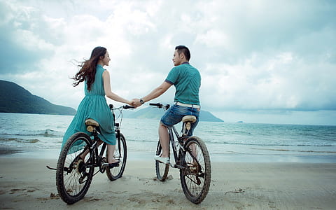man and woman riding bicycle on seashore thumbnail