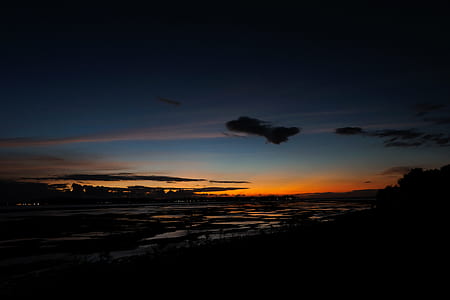 silhouette of buildings near body of water during golden hour thumbnail