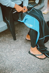 Person Unzipping Black and Teal Scuba Suit thumbnail
