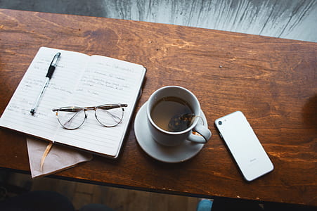 white ceramic mug with tea on white ceramic saucer on brown wooden table thumbnail