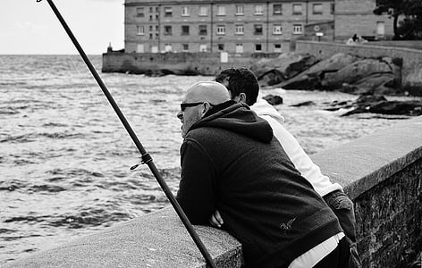 grayscale photography of two man standing beside the bay thumbnail