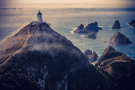 white building on top of mountain near body of water thumbnail