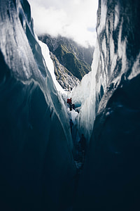 man standing on ice looking at mountain covered in clouds thumbnail