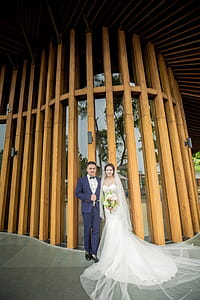 Photography of Couple Stands in Front Wooden Wall thumbnail