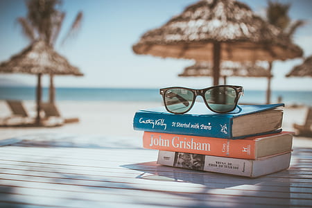 selective focus photography of three piled assorted-title reading books with brown sunglasses on top thumbnail