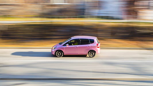 timelapse photography of pink Honda Fit 5-door hatchback on road thumbnail