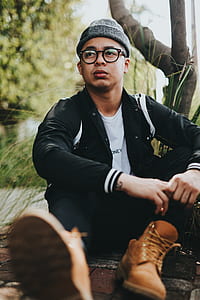 man in jacket and boots sitting near plant thumbnail
