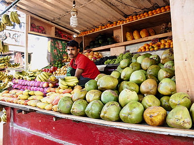 man wearing red polo shirt sitting behind fruit stand thumbnail