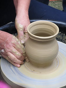 person forming vase with clay on round gray rotating clay table thumbnail