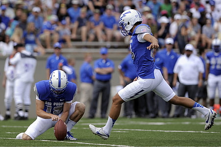 football playing holding football while other player attempt to kick thumbnail