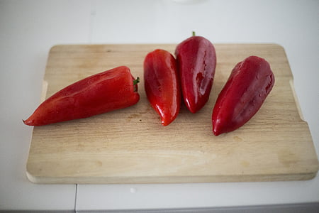 several red capsicums on top of rectangular brown wooden cutting board thumbnail
