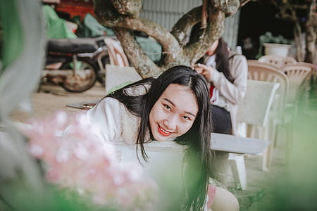 Selective Focus Photography of Woman Sitting on Chair Near Tree Branch thumbnail