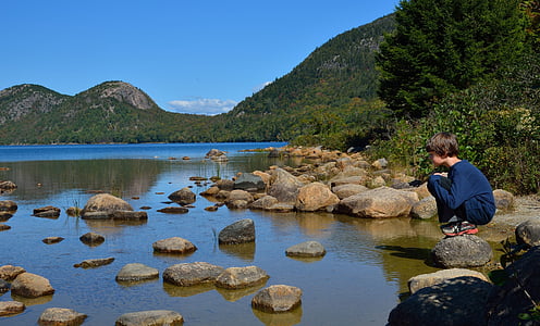 boy step on rock beside river near mountain thumbnail
