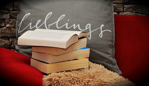 four stacked books near gray pillow thumbnail